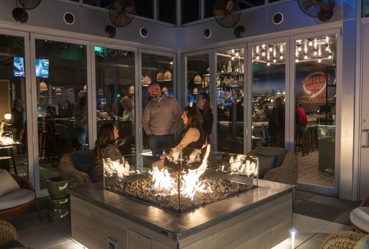 Guests seated around outdoor fire pit on rooftop patio at Prime Social