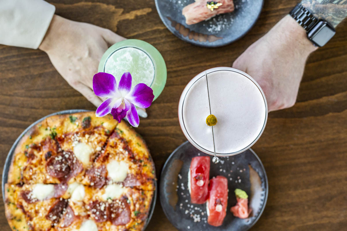 Bird’s eye view of cocktails with pizza and sushi appetizers.
